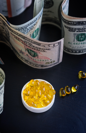 Capsules of fish oil and euro, dollars on black backgroundの写真素材