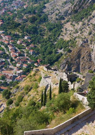 Kotor in Montenegro with view of mountains, ruins of ancient fortress and old houses with red tile roofsの写真素材