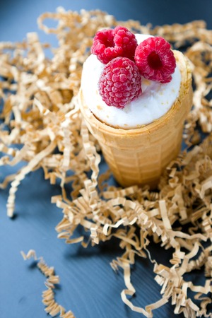 Ice cream with raspberry in waffle cone on woodの写真素材