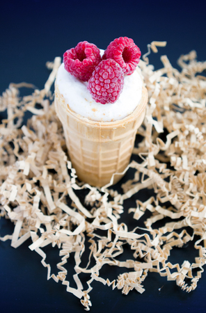 Ice cream with raspberry in waffle cone on blackの写真素材