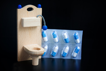 Wooden toy toilet and pills on blackの写真素材