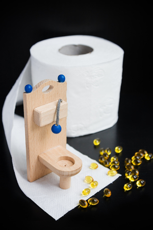 Wooden toy toilet, capsules and paper on blackの写真素材