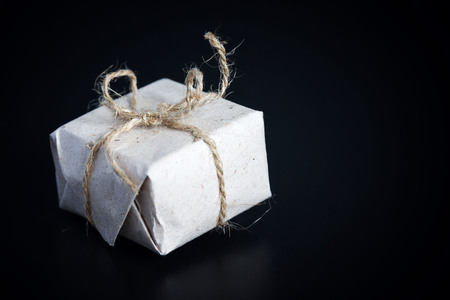 Present wrapped in plain brown paper and tied with string on blackの写真素材