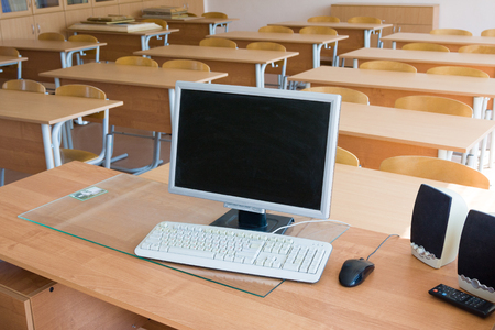 Computer on teacher`s table in classroomの写真素材