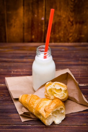 Bottle of milk and croissant on woodの写真素材