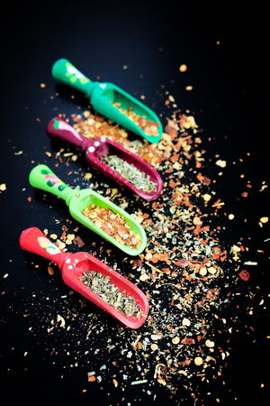 Spices and wooden spoons on black backgroundの写真素材