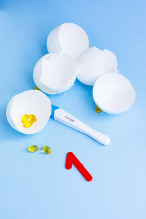 Long-awaited pregnancy after unsuccessful IVF. Positive pregnancy test, pills, eggshell and number oneの写真素材