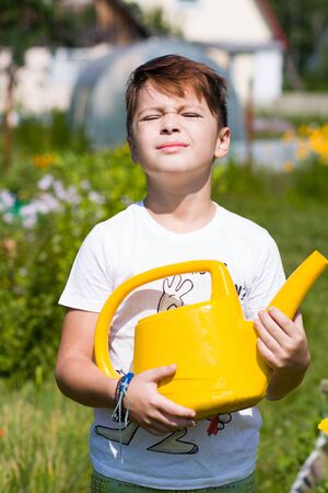Cute boy with watering can in garden in summerの写真素材