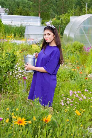 Girl with watering can in garden in summerの写真素材