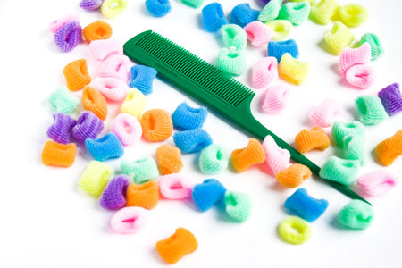 Plastic comb and bright multi-colored scrunchies on white background