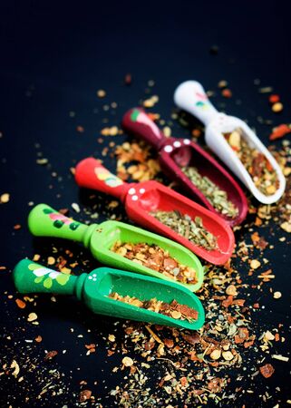 Spices and wooden spoons on black backgroundの写真素材