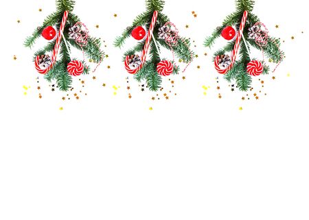 Christmas decorations and tree branch on white background. Composition collage with striped candy, red apple, cone, striped thread and confetti. Flat lay. New Year and Christmas moodの写真素材