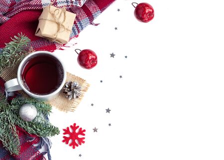Hot christmas beverage black tea in mug with new year decorations, Cone, present, silver ball, apple, fir tree, plaid on white background. Winter time top view. Copy spaceの写真素材