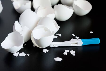 Infertility. Negative pregnancy test and eggshell on blackの写真素材