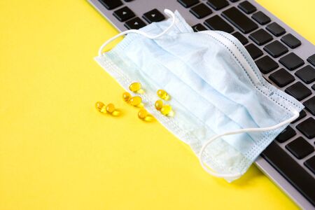 Blue cloth medical mask on computer keyboard. Home schooling and working from home during quarantine. Stay at homeの写真素材