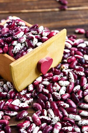 Violet with dots beans in wooden box with heart. Swallow beans. Vegetables for healthy eating. Organic food. Dietの写真素材