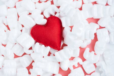 Red felt heart on white  pellets. Careful delivery with love. Tenderness. Caring with loveの写真素材