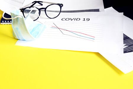 End of pandemic coronavirus and isolation. Used crumpled medical mask against glasses and chart for reducing the incidence of morbidity and mortality. Selective focusの写真素材