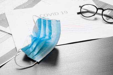 End of pandemic coronavirus and isolation. Used crumpled medical mask against glasses and chart for reducing the incidence of morbidity and mortality. Focus on maskの写真素材