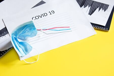 End of pandemic coronavirus and isolation. Used crumpled medical mask on chart for reducing incidence of morbidity and mortality. Focus on maskの写真素材