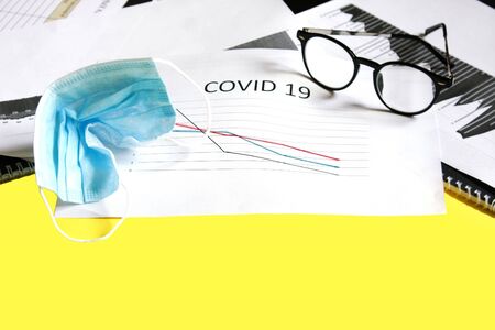 End of pandemic coronavirus and isolation. Used crumpled medical mask against glasses and chart for reducing the incidence of morbidity and mortality. Selective focusの写真素材