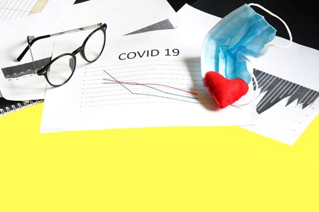 End of pandemic coronavirus and isolation. Used crumpled medical mask, glasses and felt heart on chart for reducing the incidence of morbidity and mortality. Selective focusの写真素材
