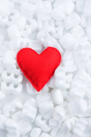 Red felt heart on white  pellets. Careful delivery with love. Tenderness.の写真素材