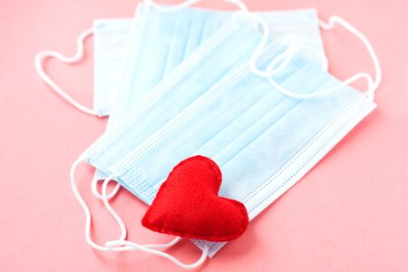 Blue cloth medical masks with red heart on pink. Brave heart and gratitude to all workers of medicine. Coronavirus, COVID-19, pandemic during quarantine. Nurse dayの写真素材
