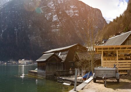 Halstatter lake in sun rays near traditional wooden boat houses and against mountains in famouse village Hallstatt, Salzkammergutの写真素材