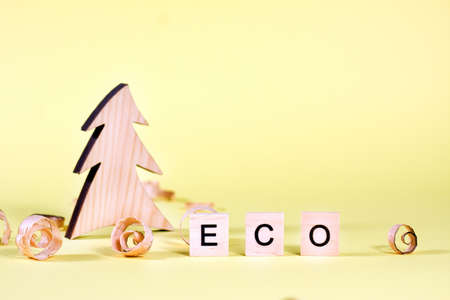 Wooden fur-tree, curled shavings and word eco on yellow. Eco toys. Save the forests, awareness concept. Environmentally friendly investments. Sawdust of woodworking industryの写真素材