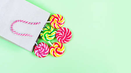 Colorful lollipops in paper bag on green background. Sweets for party. Sugarの写真素材