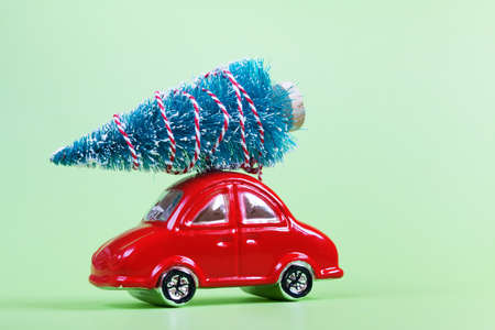 Moscow, Russia - September 25, 2020: Glass red toy car with christmas decoration on green background. Preparation for New Year and Christmas.の写真素材