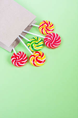 Colorful lollipops in paper bag on green background. Sweets for party. Sugarの写真素材