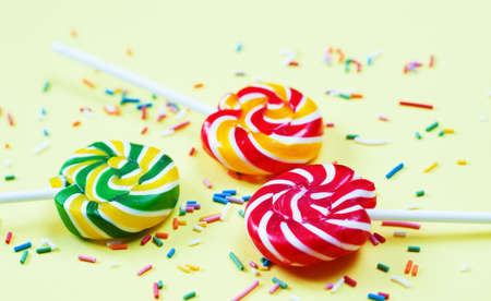 Colorful lollipops and confetti on yellow background. Sweets for party. Sugarの写真素材