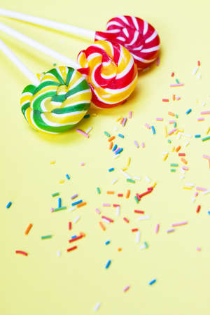 Colorful lollipops and confetti on yellow background. Sweets for party. Sugarの写真素材