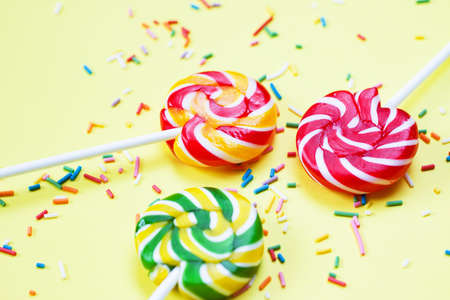 Colorful lollipops and confetti on yellow background. Sweets for party. Sugarの写真素材