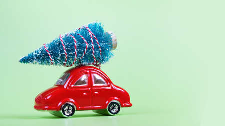 Moscow, Russia - September 25, 2020: Glass red toy car with christmas decoration on green background. Preparation for New Year and Christmas.の写真素材