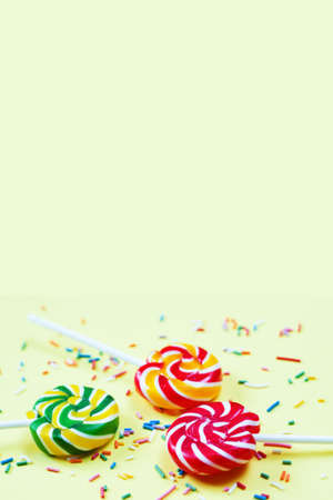 Colorful lollipops and confetti on yellow background. Sweets for party. Sugarの写真素材
