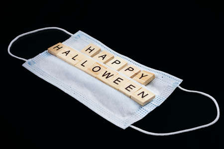 Medical mask and wooden words Happy Halloween on black. Halloween background decor holiday conceptの写真素材
