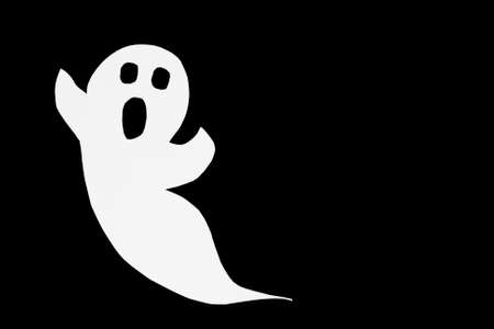 Cut out paper ghost on black. Halloween background decor holiday concept.の写真素材