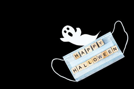 Cut out paper ghost, medical mask and words Happy Halloween on black. Halloween background decor holiday conceptの写真素材