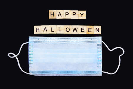 Medical mask and wooden words Happy Halloween on black. Halloween background decor holiday concept.の写真素材