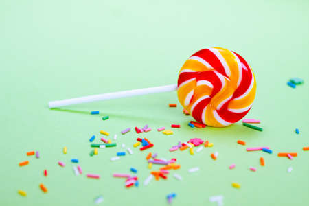 Colorful lollipop and confetti on green background. Sweets for partyの写真素材