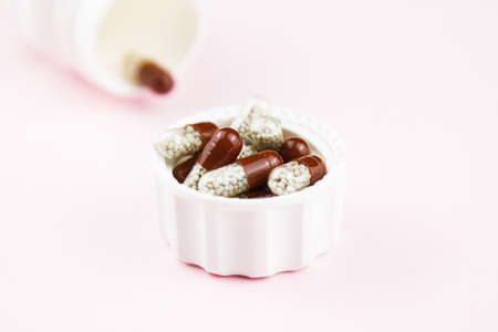 Brown soluble capsules on pink. Herbal drugs. Alternative medicine in capsule.の写真素材