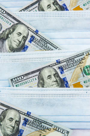 Blue medical masks and dollars.Helping poor countries with money and masks.Financial crisis due to coronavirus.Cash payments to doctors.Expensive hospital services.Sponsoring medical research.の写真素材