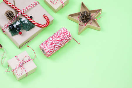 Christmas eco friendly packaging gifts on green, eco christmas holiday concept, eco decor festive winter background. Present with candy and fir-tree, paer boxes and wooden tree toy on greenの写真素材