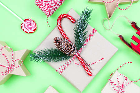 Christmas eco friendly packaging gifts on green, eco christmas holiday concept, eco decor festive winter background. Present with candy and fir-tree, paer boxes and wooden tree toyの写真素材