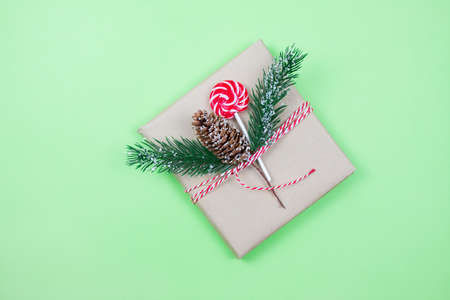 Christmas gift box wrapped in brown craft paper with corn, fir-tree and candy on green background. New Year and Christmas concept. Eco package. Focus on cornの写真素材