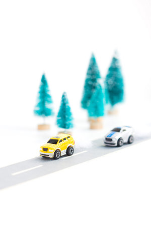Two small cars on paper road against on white background. Traffic on country road. Travel. Automotive exhaust pollutionの写真素材