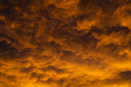 Lush, heavy clouds, painted orange by the sun at sunset. Texture.の写真素材